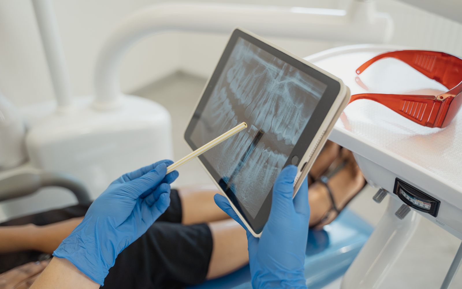 Dentista mostrando radiografia em tablet ao lado da paciente