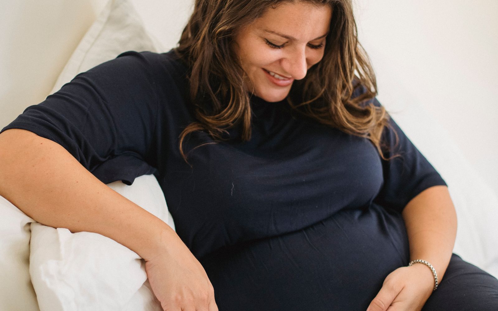 Gestante sorrindo e acariciando a barriga