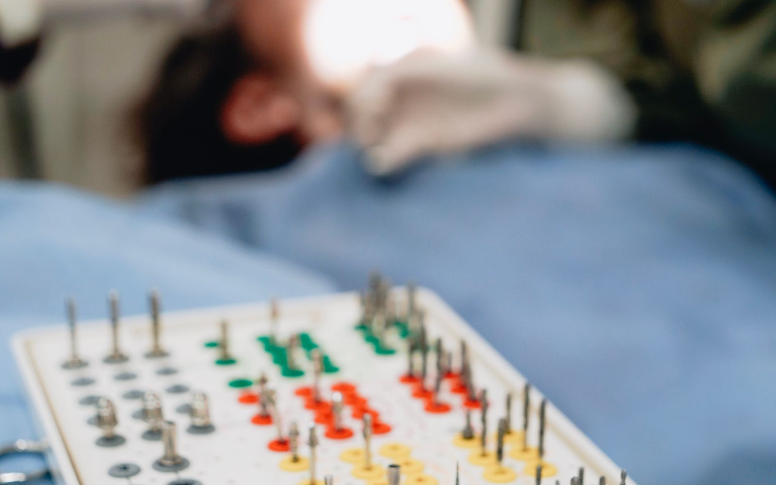 Kit cirúrgico de implantes com dentista atendendo paciente ao fundo