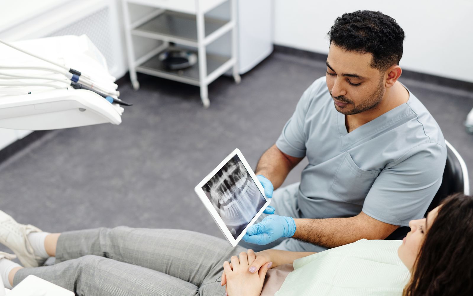 Dentista mostrando radiografia em tablet para a paciente