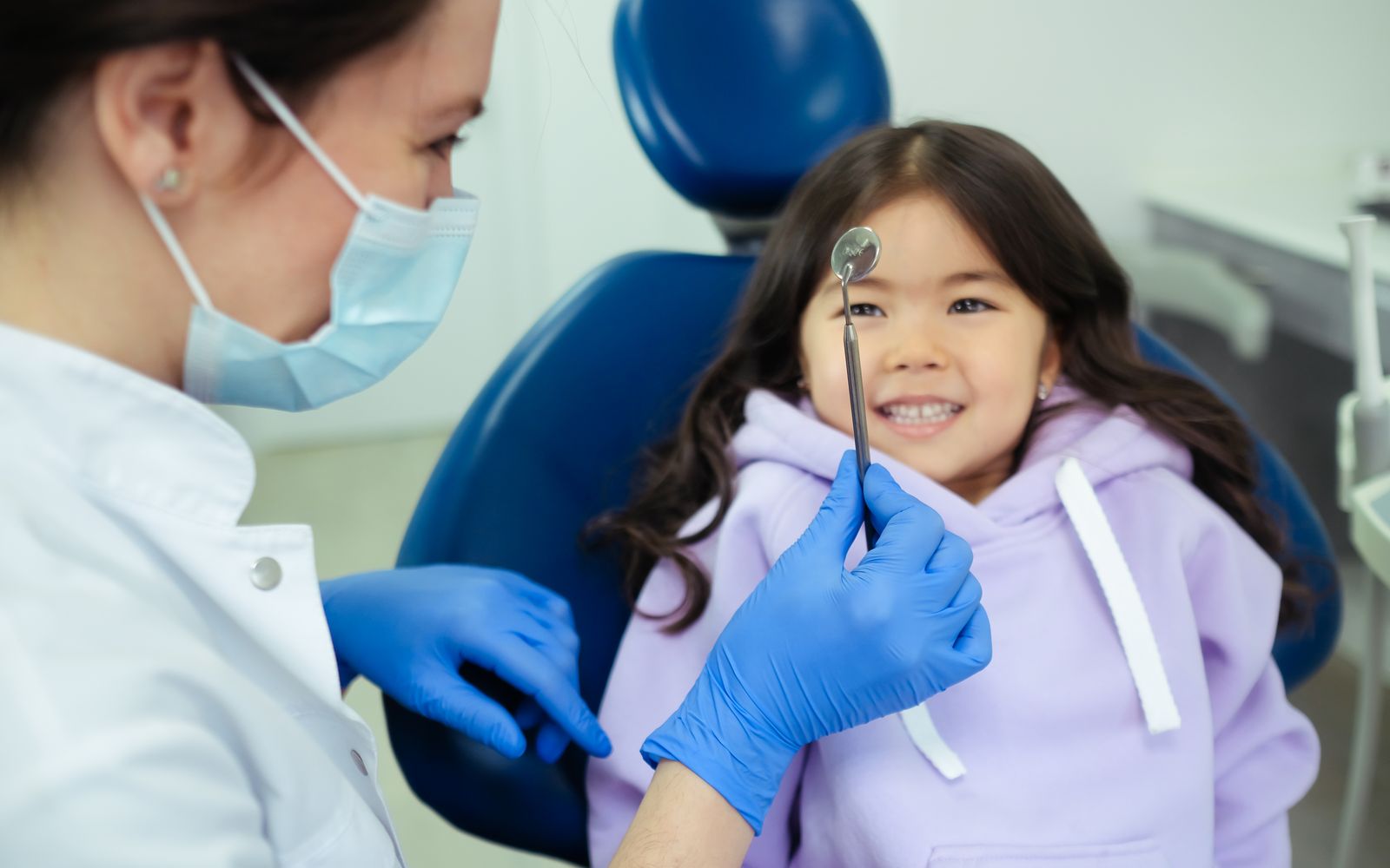 Dentista e criança sorrindo durante consulta na clínica