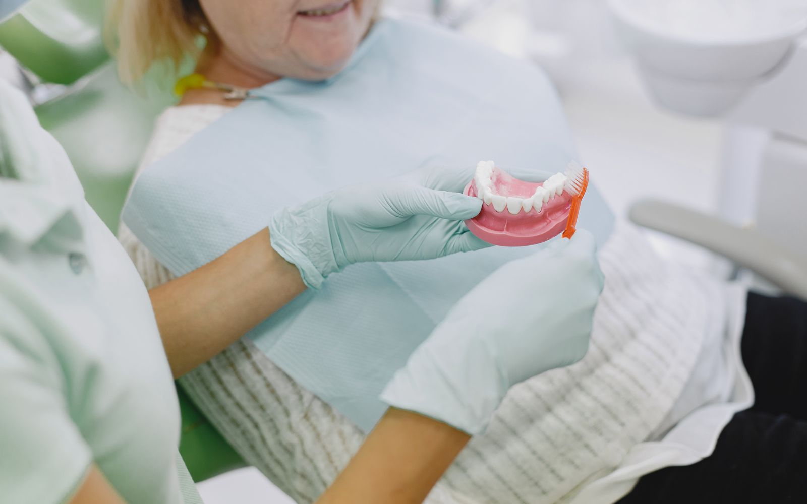 Dentista apresentando modelo de prótese dentária a uma paciente