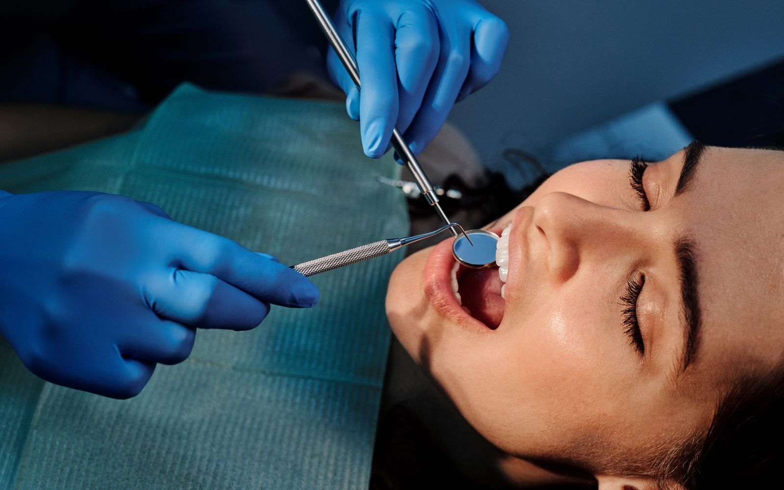 Close de exame odontológico com espelho nos dentes de uma paciente